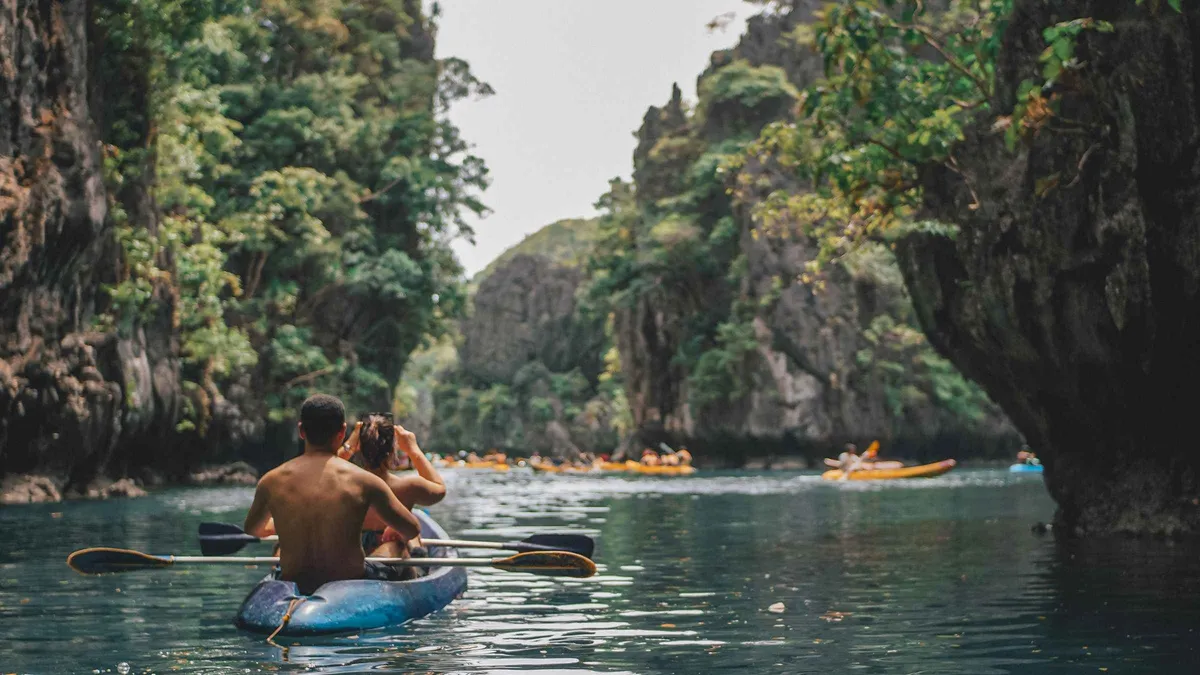 Two kayaks paddling through the narrow entrance of the Small Lagoon on an El Nido island hopping tour D, Miniloc Island, Palawan